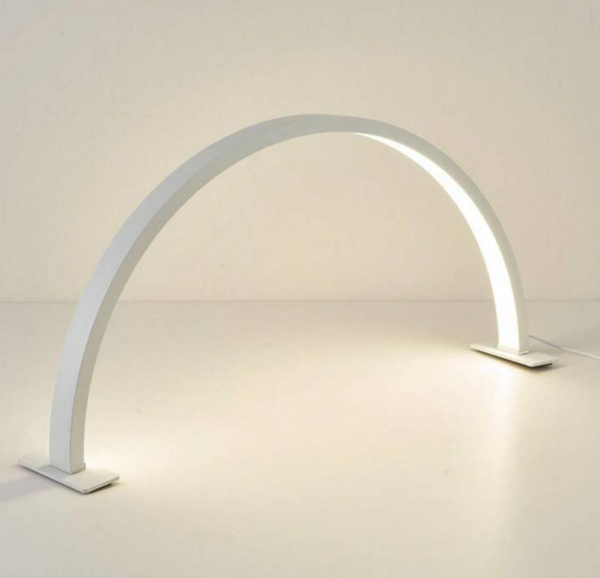 A white, arch-shaped LED nail light with a modern design, illuminated and displayed against a neutral background.